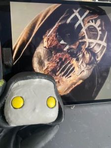 playing with the eyeholes in a layer of clay over the face of a pop vinyl being transformed into a custom Sleep token figurine.