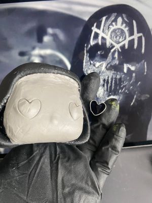 playing with the eyeholes in a layer of clay over the face of a pop vinyl being transformed into a custom Sleep token figurine.