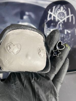 playing with the eyeholes in a layer of clay over the face of a pop vinyl being transformed into a custom Sleep token figurine.