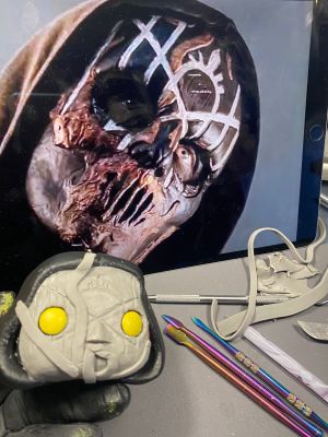 roughing in shapes in a layer of clay over the face of a pop vinyl being transformed into a custom Sleep token figurine.