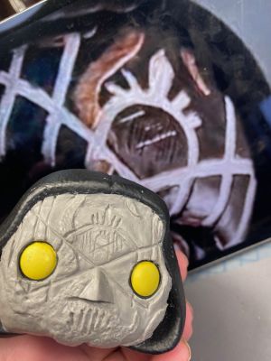 carving the sleep token sigil in a layer of clay over the face of a pop vinyl being transformed into a custom Sleep token figurine.