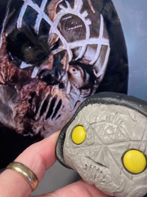 carving the sleep token sigil in a layer of clay over the face of a pop vinyl being transformed into a custom Sleep token figurine.